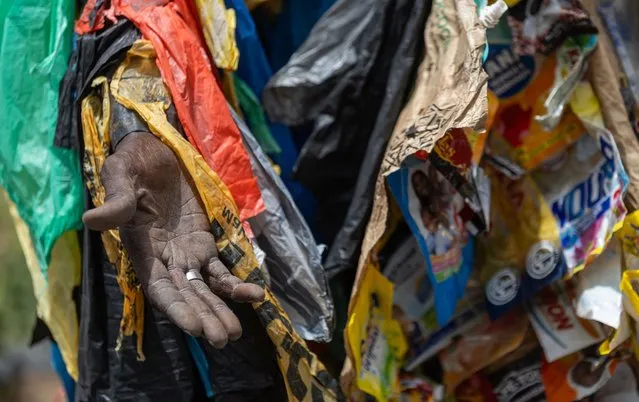 Environmental activist Modou Fall, also known as “Plastic Man”, wears his plastic suit in Guediawaye, Dakar, Senegal, 23 June 2023. For more than 15 years, Fall, a former soldier and father of three nicknamed “Plastic Man”, has been on a mission to raise the awareness of his fellow citizens about plastic waste and pollution. Fall is often seen wearing a custom made camouflage suit composed of recycled plastic bags to carry his message across and has become the international face of the fight against plastic waste and pollution in Senegal. According to Fall, 200,000 tons of plastic are collected annually in Senegal but only 9,000 tons are recycled, while the rest is burned and contributes to more environmental pollution. The sign reads “All against the silent killer, the plastic peril”. (Photo by Jérôme Favre/EPA/EFE)