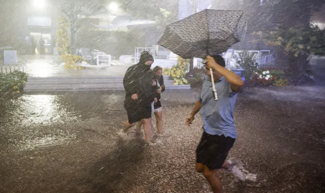 People navigate heavy rains and flooded walkways at the Billie Jean King National Tennis Center as the remnants of Hurricane Ida hit the a​rea in Flushing Meadows, New York, USA, 01 September 2021. (Photo by Justin Lane/EPA/EFE)