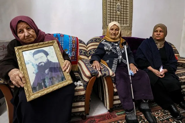 Aisha, mother of Saleh al-Aruri, sits holding a picture of him at their family house in Arura, north of Ramallah in the occupied West Bank, on January 3, 2024. Aruri, exiled from his village Arura since he was released from an Israeli jail in 2010, was killed in a drone strike on a southern Beirut suburb that Lebanese officials said was carried out by Israel. (Photo by Jaafar Ashtiyeh/AFP Photo)
