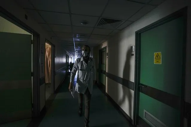 A doctor walks through a corridor of the government-run Rafik Hariri University Hospital during a power outage in Beirut, Lebanon, Wednesday, August 11, 2021. Many private hospitals, who offer 80% of Lebanon's medical services, are shutting down because of lack of resources or turning away patients who can't pay. (Photo by Hassan Ammar/AP Photo)