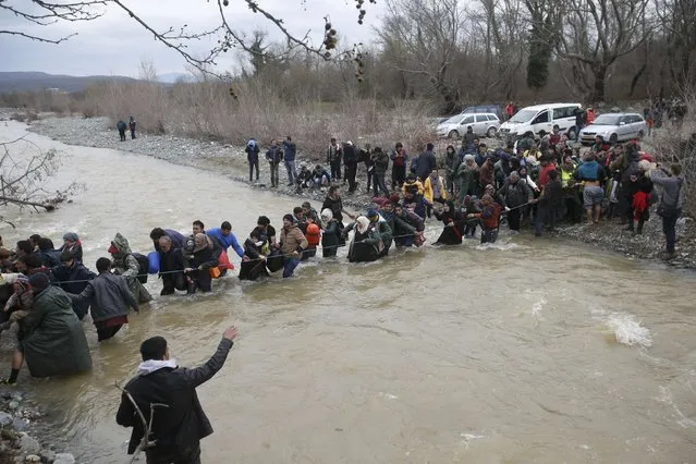 Migrants wade across a river near the Greek-Macedonian border, west of the the village of Idomeni, Greece, March 14, 2016. (Photo by Stoyan Nenov/Reuters)