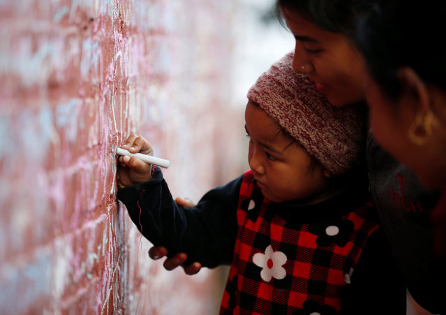 A mother helps her child write with chalk on a wall to celebrate Shreepanchami festival at Saraswati temple in Kathmandu, Nepal February 1, 2017. (Photo by Navesh Chitrakar/Reuters)