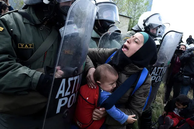 A migrant woman with a child pushing with riot police outside a refugee camp in the village of Diavata, west of Thessaloniki, northern Greece, Friday, April 5, 2019. Clashes broke out Thursday between migrants and Greek police outside a camp in northern Greece, where hundreds gathered in the hope of reviving a route that saw hundreds of thousands enter more prosperous countries in Europe. (Photo by Giannis Papanikos/AP Photo)