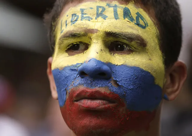 An opponent to Venezuela's President Nicolas Maduro, his face the colors of the Venezuelan national flag and the Spanish word for “Freedom” written on his forehead, takes part in a march in Caracas, Venezuela, Saturday, May 4, 2019. Opposition leader Juan Guaido took his quest to win over Venezuela's troops back to the streets, calling his supporters to participate in an outreach to soldiers outside military installations across the country. (Photo by Martin Mejia/AP Photo)