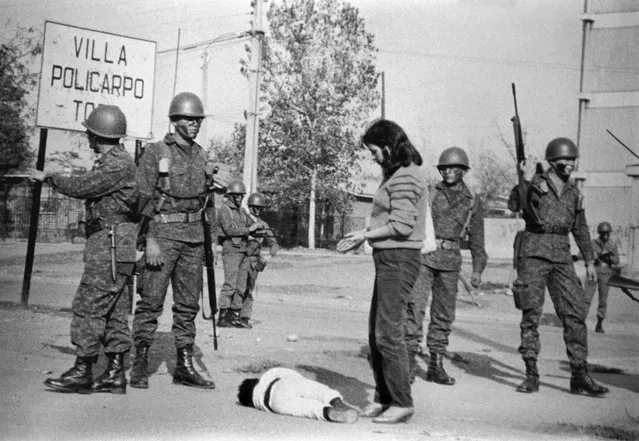 A woman's son lays on the ground crying after his father was arrested as soldiers carry out a military operation in the San Miguel area of Santiago, Chile, May 1986. (Photo by Marco Ugarte/AP Photo)