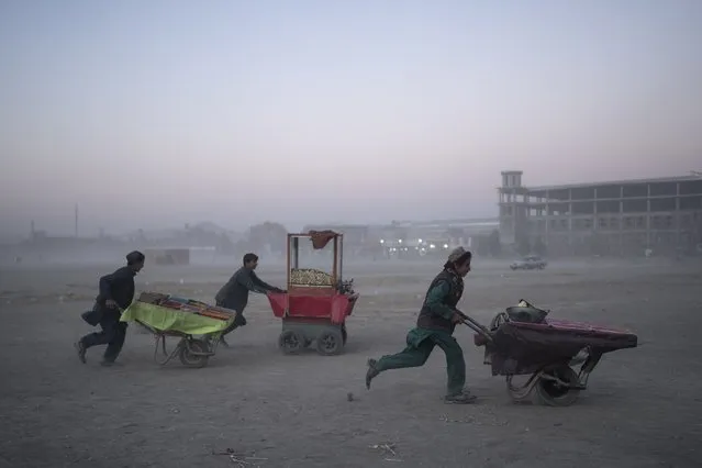Street vendors run with their carts in Chaman-e-Hozori park, Kabul, Afghanistan, Friday, November 19 , 2021. (Photo by Petros Giannakouris/AP Photo)
