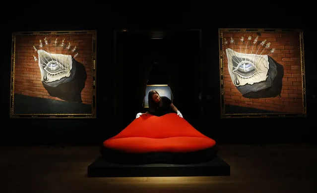 A Christie's employee adjusts a sofa called “Mae West Lips Sofa” made by Salvador Dali and Edward James, in front of Salvador Dali's paintings “L'oiel fleuri, decor pour le ballet Trist” at Christie's in London, Friday, February 24, 2017. The paintings and the sofa belong to the evening sale entitled “The Art of the Surreal” on Tuesday Feb. 28. The sofa is estimated to fetch 400,000-600,000 GBP ($510,000-750,000 and 470,000-700,000Euro) while the paintings are estimated to fetch 350,000-550,000 GBP, ($440,000-690,000 and 420,000-650,000 Euro.) (Photo by Frank Augstein/AP Photo)