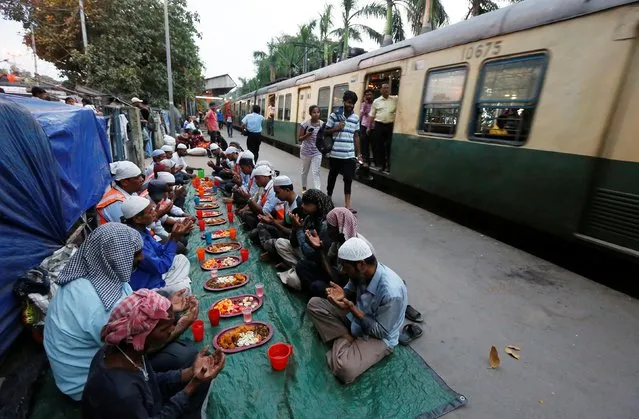 Muslim men pray as they sit before their iftar (breaking of fast) meal next to a train passing on a railway platform during the holy fasting month of Ramadan, in Kolkata, India May 13, 2019. (Photo by Rupak De Chowdhuri/Reuters)