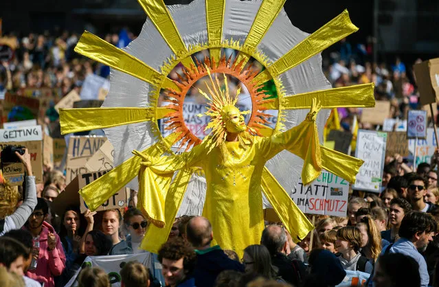 Youth climate activists, with one of them dressed up as a sun, protest with placards as they take part in the “Fridays for Future” demonstration for a better climate policy in front of the cathedral of Cologne, western Germany, on May 24, 2019. The Youth climate action group calls for record mobilisation ahead of the May 26 European elections. (Photo by  Ina Fassbender/AFP Photo)