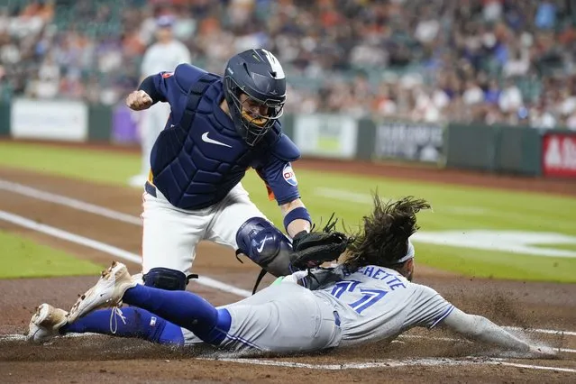Toronto Blue Jays' Bo Bichette, bottom, is tagged out at home by Houston Astros catcher Victor Caratini during the first inning of a baseball game Tuesday, April 2, 2024, in Houston. (Photo by Eric Christian Smith/AP Photo)