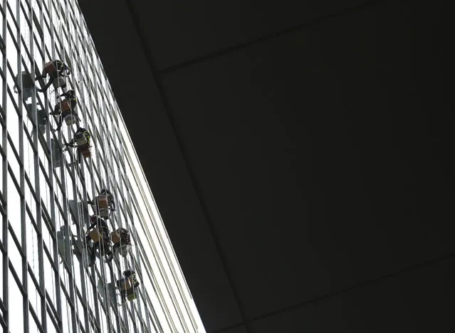 Workers hang on the ropes to attach silicone to windows on a building in Seoul, South Korea, Wednesday, May 29, 2019. (Photo by Ahn Young-joon/AP Photo)