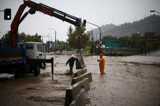 Workers prepare a barrier on a flooded street in Santiago, April 17, 2016. (Photo by Ivan Alvarado/Reuters)