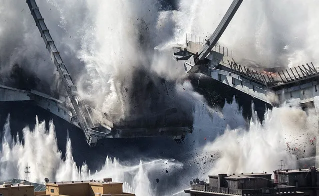 A cloud of dust rises as the remaining spans of the Morandi bridge are demolished in a planned expolosion, in Genoa, Italy, Friday, June 28, 2019. The spectacular planned explosion knocked down the remaining spans and supporting columns of the Italian bridge that collapsed last year, killing 43 people and some 3,500 people who live nearby had been evacuated as a precaution in the last hours; sirens sounded a final warning. (Photo by Luca Zennaro/ANSA via AP Photo)