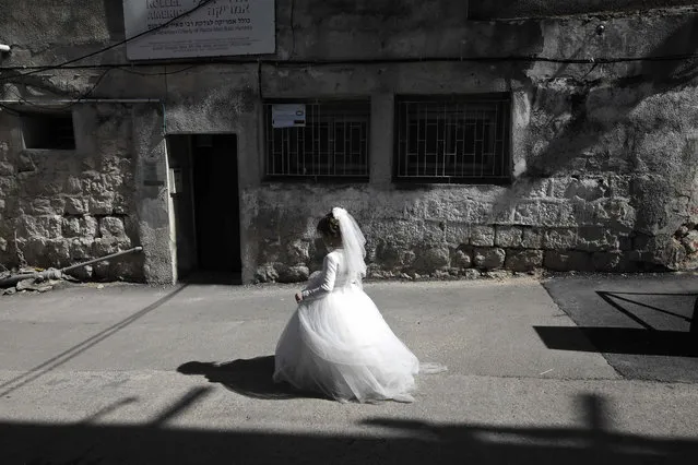An ultra-Orthodox Jewish girl wearing a bride outfit walks in the street during a school Purim celebration four days ahead of the official holiday on the Jewish calendar in the ultra-Orthodox Jewish neighbourhood of Mea Shearim in Jerusalem on March 8, 2017. The carnival-like Purim holiday is celebrated with parades and costume parties to commemorate the deliverance of the Jewish people from a plot to exterminate them in the ancient Persian empire 2,500 years ago, as recorded in the Biblical Book of Esther. (Photo by Menahem Kahana/AFP Photo)