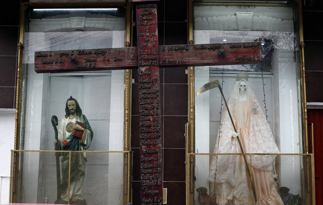 In this March 5, 2017 photo, a statue of Saint Judas Thaddeus, left, sands next to the Death Saint, or “Santa Muerte”, inside niches at Mercy Church on the edge of Mexico City's Tepito neighborhood. As veneration of Santa Muerte becomes more accepted, shrines can also be found in the back of all kinds of stores and gas stations. (Photo by Marco Ugarte/AP Photo)