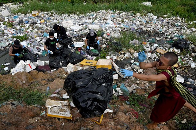 Volunteer students and Buddhist monks collect plastic waste from a sewage canal to set an example and educate people on proper plastic disposal in Phnom Penh on October 28, 2023. (Photo by Tang Chhin Sothy/AFP Photo)