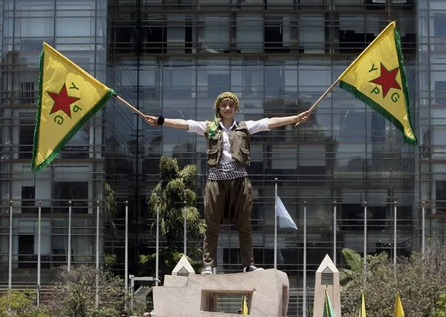 A Kurdish girl who lives in Lebanon waves flags of the Kurdish People's Protection Units, also known as YPG, during a demonstration in solidarity with their Kurdish brethren in northern Syria who are fighting against Islamic State group militants, in front of the United Nations headquarters in Beirut, Lebanon, Sunday, July 5, 2015. (Photo by Bilal Hussein/AP Photo)