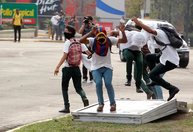 Students stomp on a billboard during a protest to demand the government to repeal a law that requires high school seniors to teach at least two people to read and write, as part of a graduation programme in Tegucigalpa, Honduras, May 4, 2016. (Photo by Jorge Cabrera/Reuters)