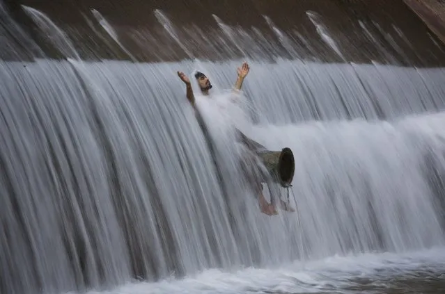 A man cools off himself during a hot weather at a dam on the outskirts of Islamabad, Pakistan, Monday, July 13, 2015. Many cities in Pakistan are facing heat wave conditions with temperatures reaching 49 degrees Celsius (120.2 Fahrenheit) in some places. (Photo by B. K. Bangash/AP Photo)