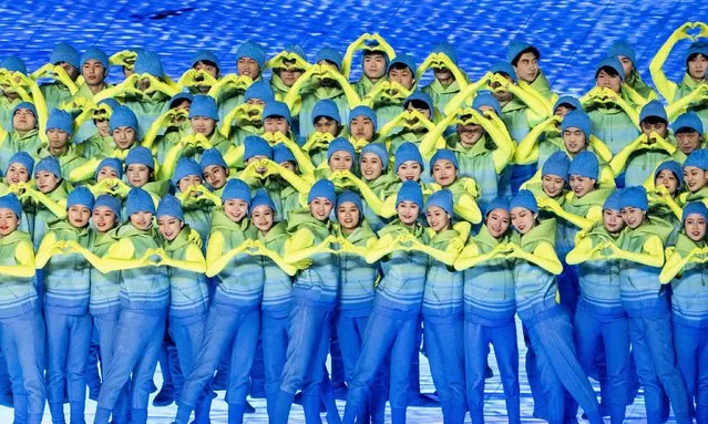 Artists form hearts with their hands as they perform in the colors of Ukraine during the closing ceremony of the Beijing 2022 Pa​ralympic Winter Games in Beijing, China, 13 March 2022. (Photo by Ennio Leanza/EPA/EFE)