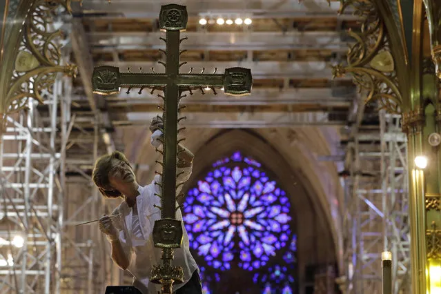 Lucia Popian, president of G&L Popian, cleans and polishes the crucifix on the main altar, Friday, July 17, 2015, as part of the of the ongoing $177 million restoration of St. Patrick's Cathedral in New York. The renovation, done in three phases over three years, started in 2012 and is slated to be finished before the Pope's visit in September 2015. (Photo by Mary Altaffer/AP Photo)