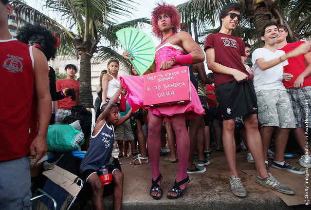 A boy lifts a Brazilian reveler's skirt during Carnival celebrations along Ipanema beach in Rio de Janiero