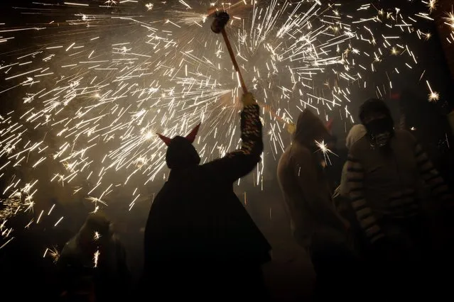 Revelers hold fireworks as they take part in a “Correfoc” – Run with Fire - party in Barcelona, Spain, Saturday, May 21, 2016. Correfocs or “fire-runs” originate from a form of medieval street theatre that represents the fight of good against evil through parades using fireworks and effigies of the devil. (Photo by Emilio Morenatti/AP Photo)