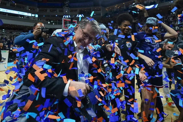Connecticut head coach Geno Auriemma celebrates with players after defeating NC State in double overtime in the East Regional final college basketball game of the NCAA women's tournament, Monday, March 28, 2022, in Bridgeport, Conn. (Photo by Frank Franklin II/AP Photo)