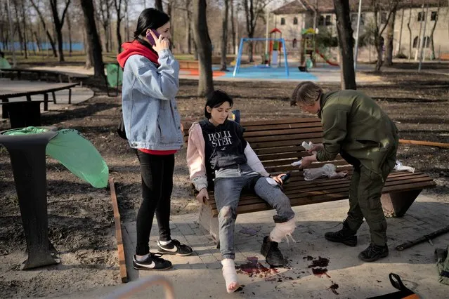 A teenage girl waits for an ambulance after being injured in a Russian attack at a public park in Kharkiv, Ukraine, Friday, April 15, 2022. (Photo by Felipe Dana/AP Photo)
