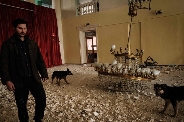 An internally displaced man walks with dogs in the destroyed building of the Palace of culture by shelling in Rubizhne, eastern Ukraine, on April 23, 2022 amid the Russian invasion of Ukraine. (Photo by Yasuyoshi Chiba/AFP Photo)