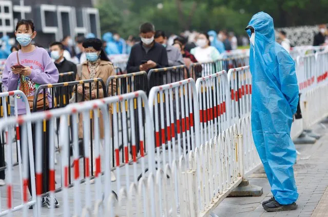 People wearing face masks line up to take nucleic acid tests at a makeshift testing site following the coronavirus disease (COVID-19) outbreak in Beijing, China on April 25, 2022. (Photo by Carlos Garcia Rawlins/Reuters)