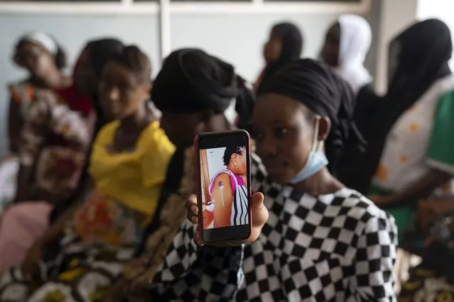 Oumie Nyassi shows a video circulating on the internet and that has been confirmed as fake news of a woman claiming she was magnetized after receiving the COVID-19 vaccine, in a doctors office at Serrekunda, Gambia hospital, Thursday September 23, 2021. Nyassi, 24, said that she would get the vaccine only after delivering her baby. As health officials in Gambia and across Africa urge women to be vaccinated, they've confronted hesitancy among those of childbearing age. Although data on gender breakdown of vaccine distribution are lacking globally, experts see a growing number of women in Africa's poorest countries consistently missing out on vaccines. (Photo by Leo Correa/AP Photo)