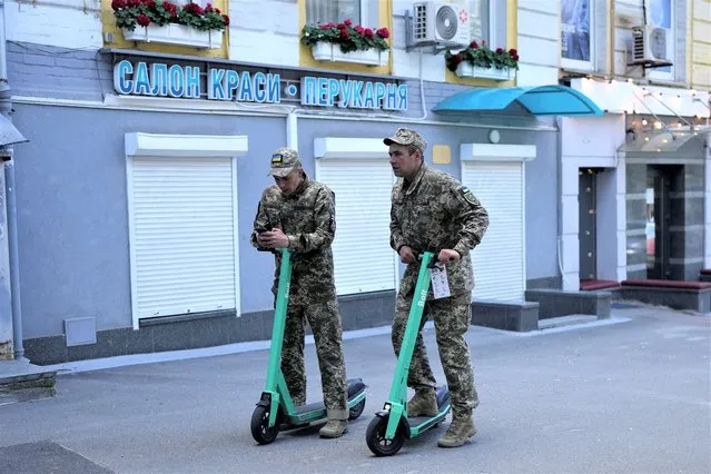Two soldiers ride scooters during Kyiv Day celebrations in Kyiv, Ukraine, Sunday, May 29, 2022. (Photo by Natacha Pisarenko/AP Photo)