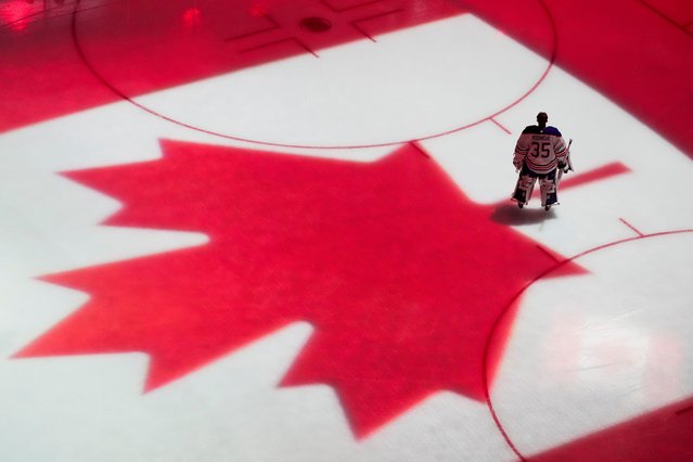 Edmonton Oilers goaltender Olivier Rodrigue stands on the ice as the flag of Canada is projected during the Canadian national anthem before a preseason NHL hockey game against the Seattle Kraken, Wednesday, October 2, 2024, in Seattle. (Photo by Lindsey Wasson/AP Photo)