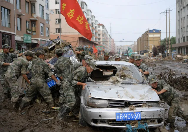 Rescue workers drag damaged cars out of debris and mud after a flood in Yongji, Jilin province, China July 17, 2017. (Photo by Yang Zaixin/Reuters/CNS)