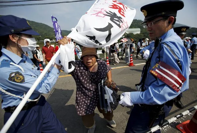 A protester is stopped by police officers during a march against the restarting of the plant in front of an entrance of Kyushu Electric Power's Sendai nuclear power station in Satsumasendai, Kagoshima prefecture, Japan, August 9, 2015. Japan is due to switch on a nuclear reactor for the first time in nearly two years as Prime Minister Shinzo Abe seeks to reassure a nervous public that tougher standards mean the sector is now safe after the Fukushima disaster in 2011. (Photo by Issei Kato/Reuters)