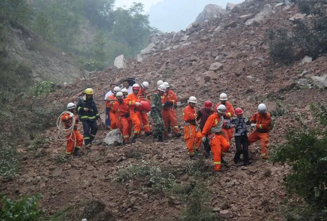 Rescue workers remove people from the site after a landslide hit a mining factory in Shanyang county, Shaanxi province, August 12, 2015. (Photo by Reuters/China Daily)