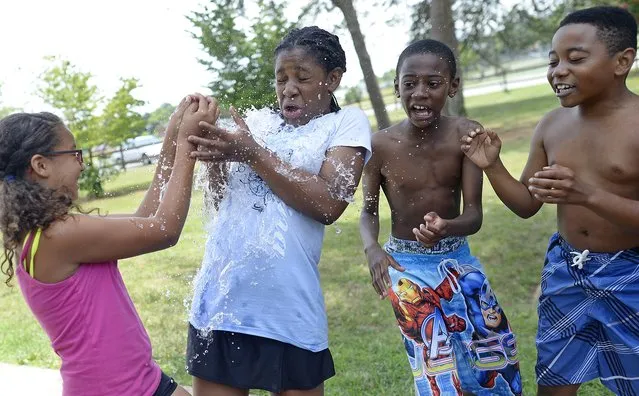 Amiya Ingram jumps as a water balloon pops on her as she and other campers play “hot potato” at Fairchild Day Camp, based at Fairchild Park in Burlington, N.C., on Wednesday, July 16, 2014. (Photo by Scott Muthersbaugh/AP Photo/Burlington Times-News)