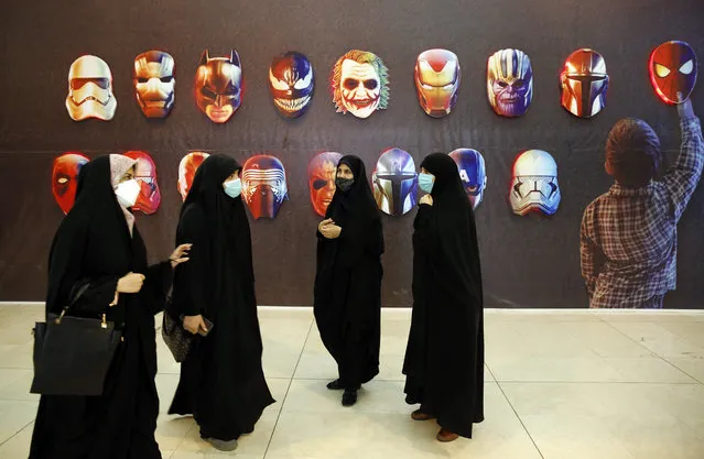 Women stand next to illustrations of comics' superheroes and villains symbolizing the western propaganda, during the Koran exhibition at Mosalah mosque in Tehran, Iran, 17 April 2022. The exhibition runs until 29 April. (Photo by Abedin Taherkenareh/EPA/EFE)