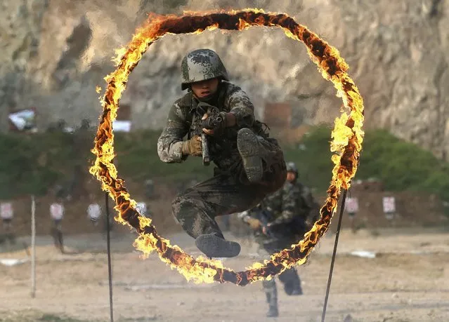 A member of People's Liberation Army (PLA) coastal defence force jumps through a burning obstacle during a drill to mark the 87th Army Day at a military base in Qingdao, Shandong province July 29, 2014. The PLA Army Day falls on August 1 every year. Chinese President Xi Jinping has pledged to strike hard against graft in the military, urging soldiers to banish corrupt practices and ensure their loyalty to the ruling Communist Party, state media reported on Friday. (Photo by Reuters/Stringer)