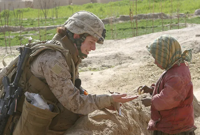 Second Lt. Johanna Shaffer shares a cookie with an Afghan child while under the security of Marines assigned to 3rd Battalion, 8th Marine Regiment (Reinforced), during her all-female team's first mission in Farah Province, February 9, 2009. (Photo by Monty Burton/Reuters/U.S. Marine Corps)