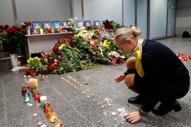 A collegue of the flight crew members of the Ukraine International Airlines Boeing 737-800 plane that crashed in Iran, places candle at a memorial at the Boryspil International airport outside Kiev, Ukraine on January 8, 2020. (Photo by Valentyn Ogirenko/Reuters)