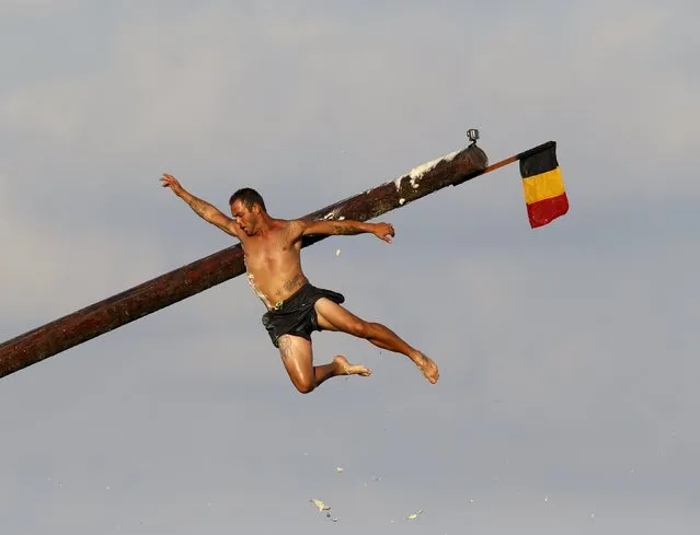 A competitor falls off the “gostra”, a pole covered in grease, after slipping and hitting against the pole during the celebrations for the religious feast of St Julian, patron of the town of St Julian's, outside Valletta, August 30, 2015. (Photo by Darrin Zammit Lupi/Reuters)