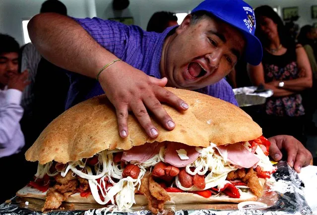 A man strikes a pose in front of a giant torta, or sandwich, during a press conference to promote the 13th annual Torta Festival, in Mexico City, Wednesday, July 20, 2016. The five day festival presents a variety of the Mexican street food made from the most exotic ingredients that include ostrich or stingray, to the classic ham, grilled steak or slow cooked pork. The festival's purpose is to maintain the tradition of eating tortas, and promote the vendors of the Mexican sandwich. (Photo by Marco Ugarte/AP Photo)