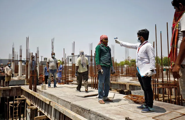 A health worker uses an infrared thermometer to measure the temperature of a labourer at the construction site of a residential building during a nationwide lockdown to slow the spreading of coronavirus disease (COVID-19) in Ahmedabad, India, April 30, 2020. (Photo by Amit Dave/Reuters)