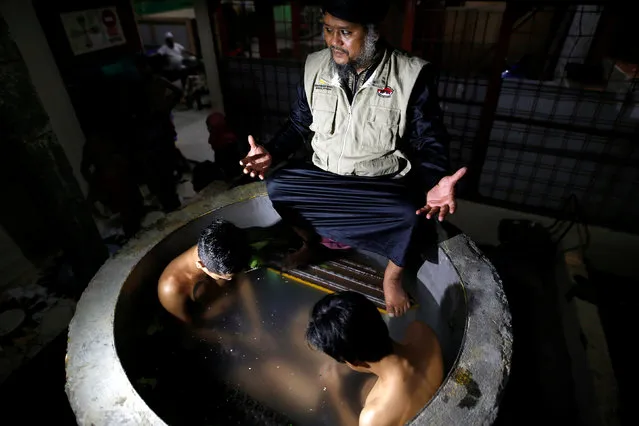The head of a traditional drug addiction treatment center, Ustad Ahmad Ischsan Maulana, prays with two recovering drug addicts who sit immersed in a herbal bath in Purbalingga, Central Java, Indonesia July 27, 2016. The traditional rehabilitation centre in a village in central Java claims to have treated hundreds of addicts with a routine of herbal teas, baths, prayer, and counselling. (Photo by Darren Whiteside/Reuters)