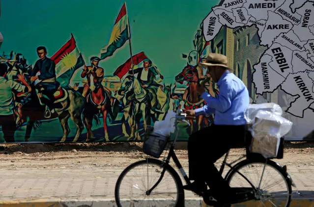 A man rides a bike near a mural supporting the referendum for independence of Kurdistan in Erbil, Iraq September 24, 2017. (Photo by Alaa Al-Marjani/Reuters)