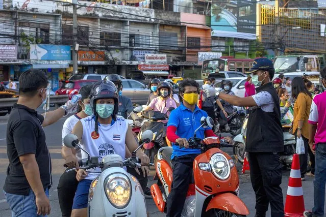 Policemen and volunteers measure body temperatures of visitors entering a market in in Bangkok, Thailand, Tuesday, May 12, 2020. Thai government continue to ease restrictions in capital Bangkok that were imposed weeks ago to combat the spread of COVID-19. (Photo by Gemunu Amarasinghe/AP Photo)