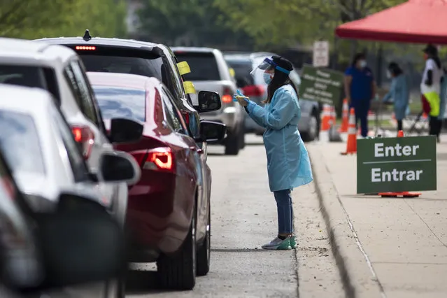 A worker instructs people on how to collect their own nasopharyngeal swab samples to test for the coronavirus at a drive-thru testing site organized by the nonprofit organization Community Organized Relief Effort (CORE) at Dr. Jorge Prieto Math and Science Academy in Chicago on Monday, May 18, 2020. (Photo by Ashlee Rezin Garcia/Chicago Sun-Times via AP Photo)