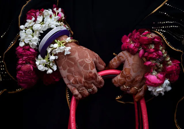 An Indian Muslim pilgrim whose hands are decorated with henna and garlands is phhotographed before leaving for the annual Hajj pilgrimage to the Holy city of Mecca at the airport in New Delhi on August 9, 2016. The Hajj, the largest annual pilgrimage in the world, is the fifth pillar of Islam, a religious duty that must be carried out at least once in the lifetime of every able-bodied Muslim who can afford to do so. (Photo by Sajjad Hussain/AFP Photo)